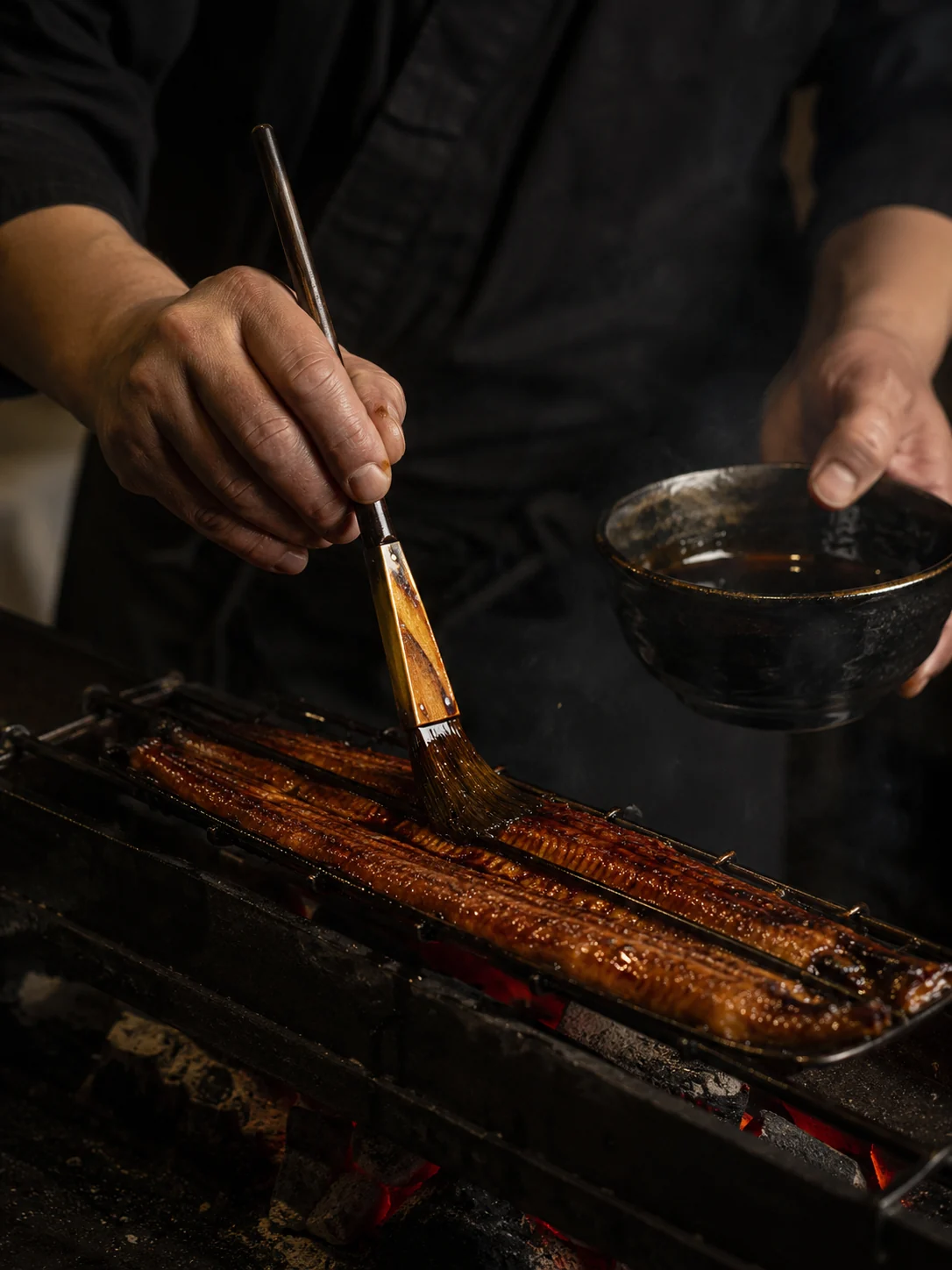 焼き上げた蒲焼にタレを重ねる職人の手元